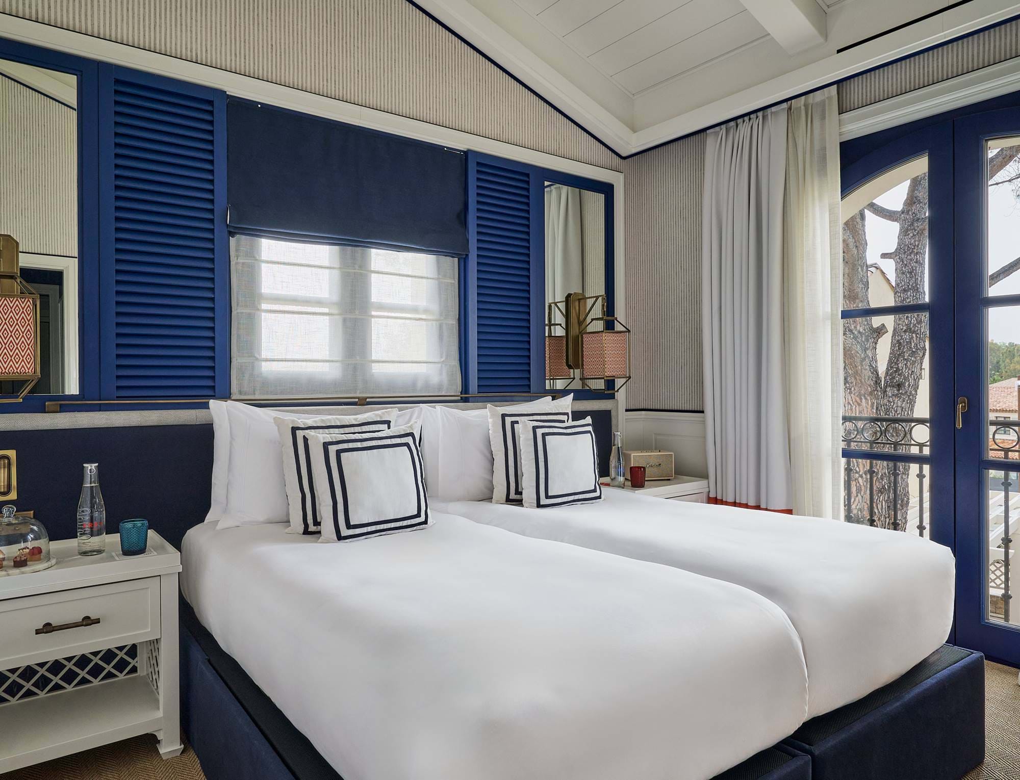 Lichtdurchflutetes Luxusschlafzimmer im AREV Hotel in Saint-Tropez mit zwei Einzelbetten, blau-weißer Einrichtung und privatem Balkon.