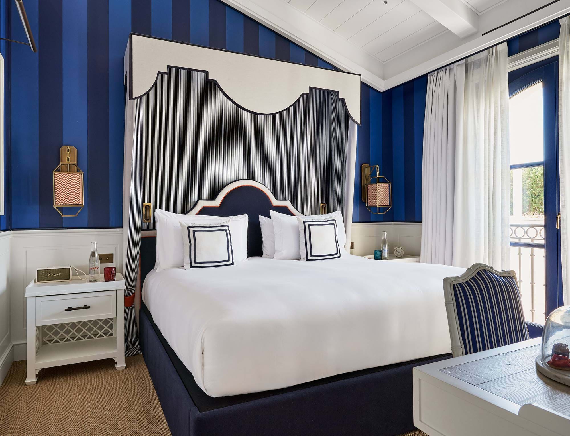 Prestige-Suite im AREV Hotel in Saint-Tropez mit Kingsize-Himmelbett, blau gestreifter Tapete und klassischen Möbeln.