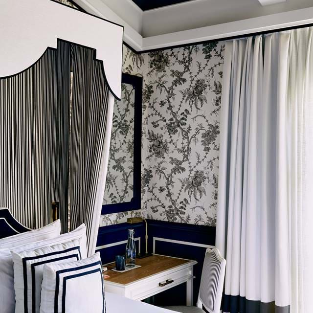 Detail eines Schreibtischbereichs und eines Designer-Himmelbetts in einer Suite im AREV Hotel in St. Tropez mit weißen Fronten und strukturierten Wänden.