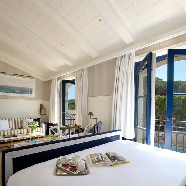 Helles Schlafzimmer im Dachgeschoss im AREV Hotel in St. Tropez. Das Frühstück wird auf dem Bett serviert und französische Türen führen auf einen Balkon.