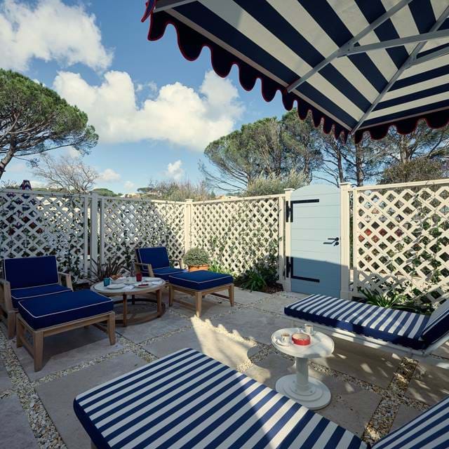 Private Terrasse und Außenterrasse im AREV Hotel in St. Tropez mit Liegestühlen unter einer marineblauen gestreiften Markise.