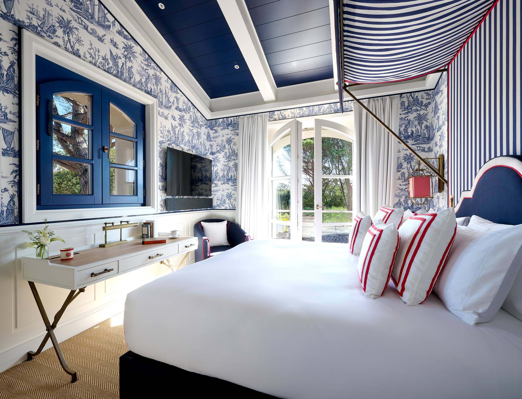 Helles Luxusschlafzimmer im AREV Hotel in Saint-Tropez mit Kingsize-Bett, elegantem blau-weißem Dekor und privater Terrasse.