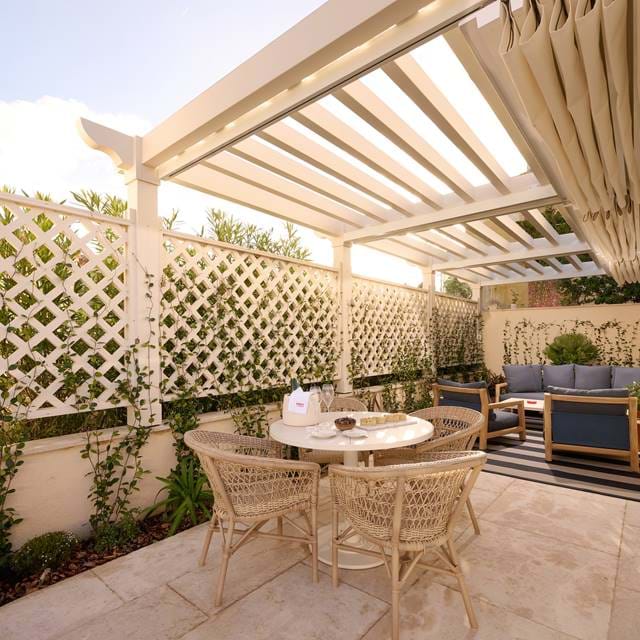 Luxuriöse Außenterrasse im AREV Hotel in Saint-Tropez mit einer bioklimatischen Pergola, Rattan-Gartenmöbeln und einem komfortablen Loungebereich.