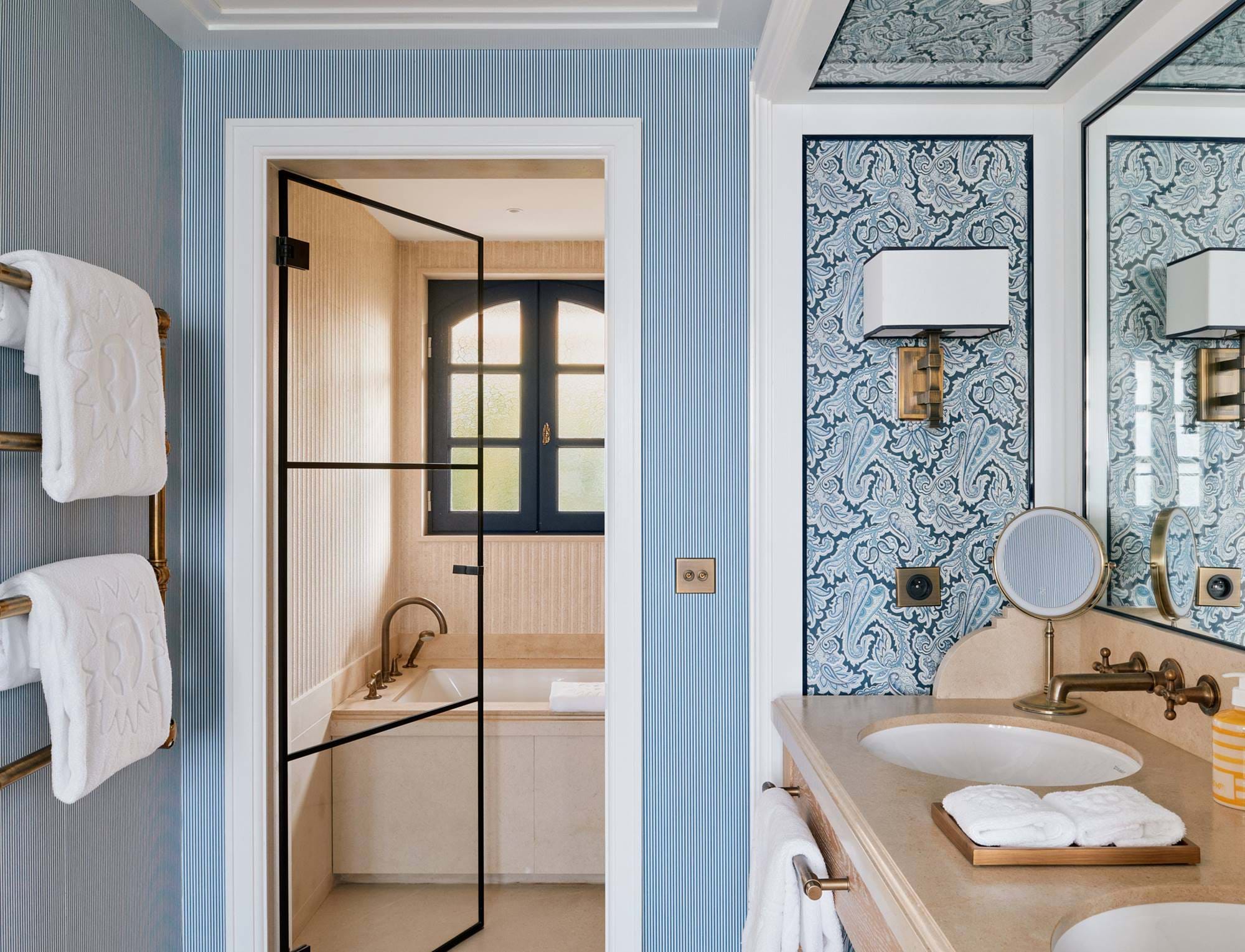 Banheiro elegante com pia dupla, papel de parede estampado e banheira de imersão no hotel AREV em Saint-Tropez.