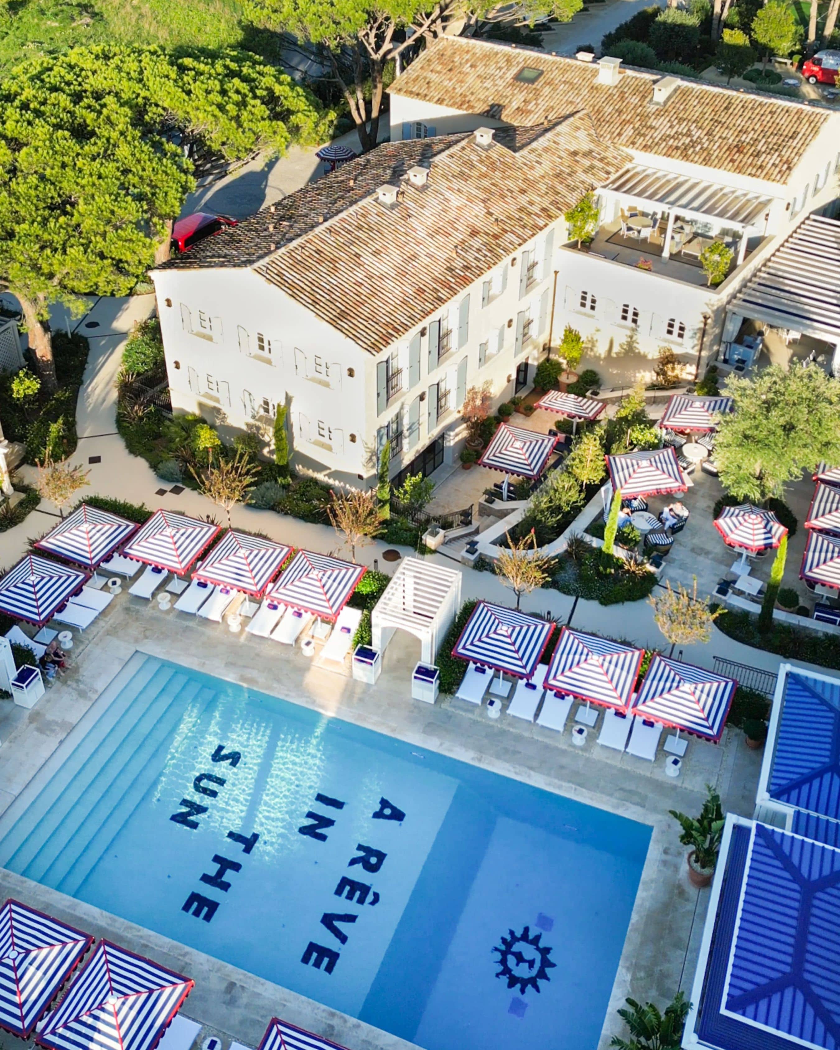 Aerial shot of a hotel pool area with striped umbrellas
