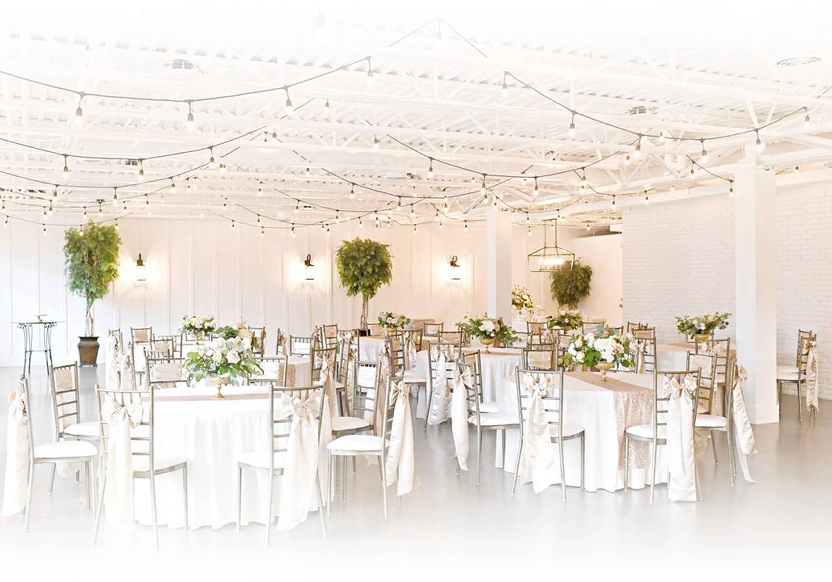 Elegant wedding reception setup with tables, floral arrangements, and bistro lighting at 5th East Hall.
