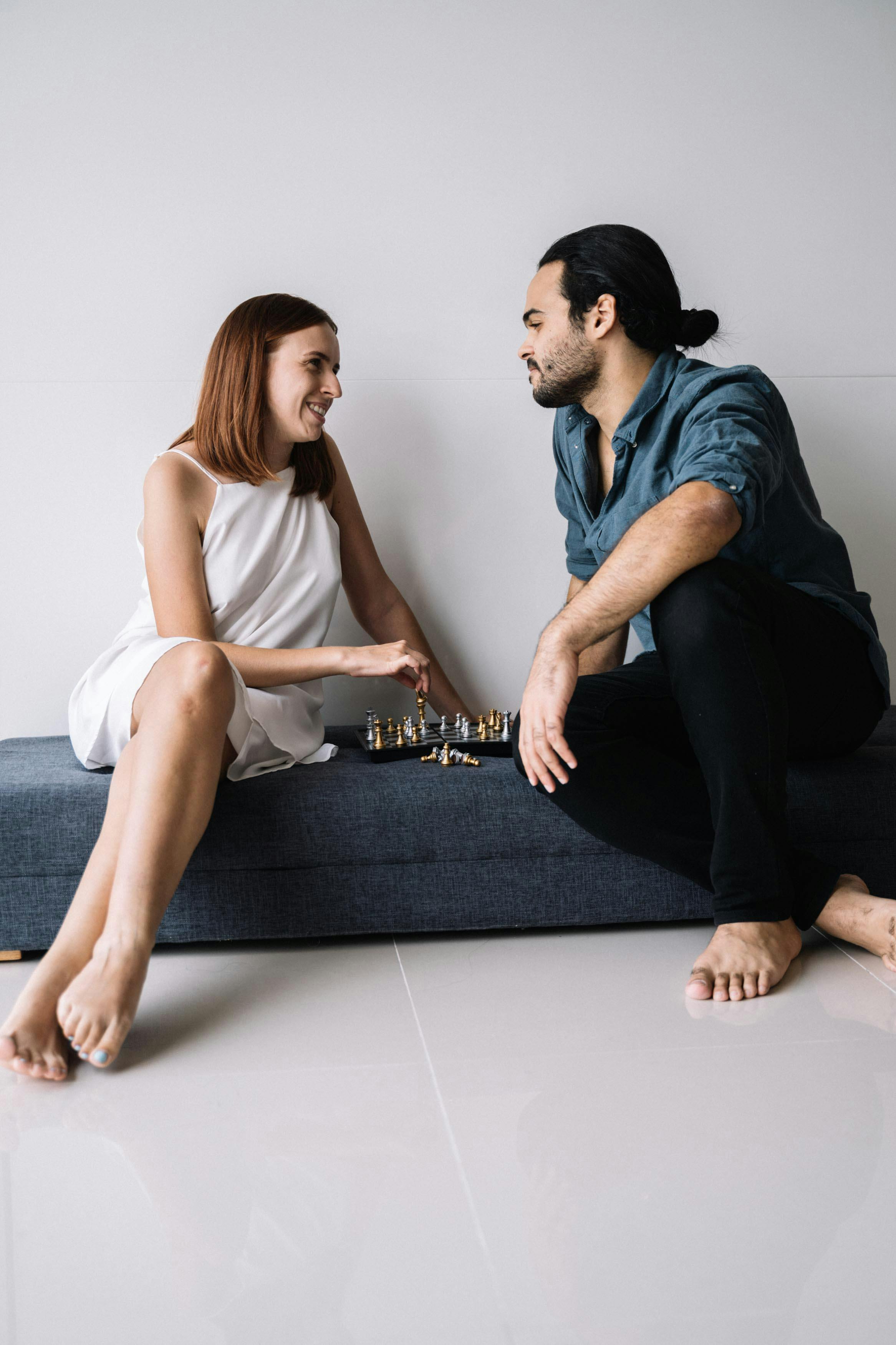 Smiling woman in white t-shirt holding and using a laptop against a light blue background.