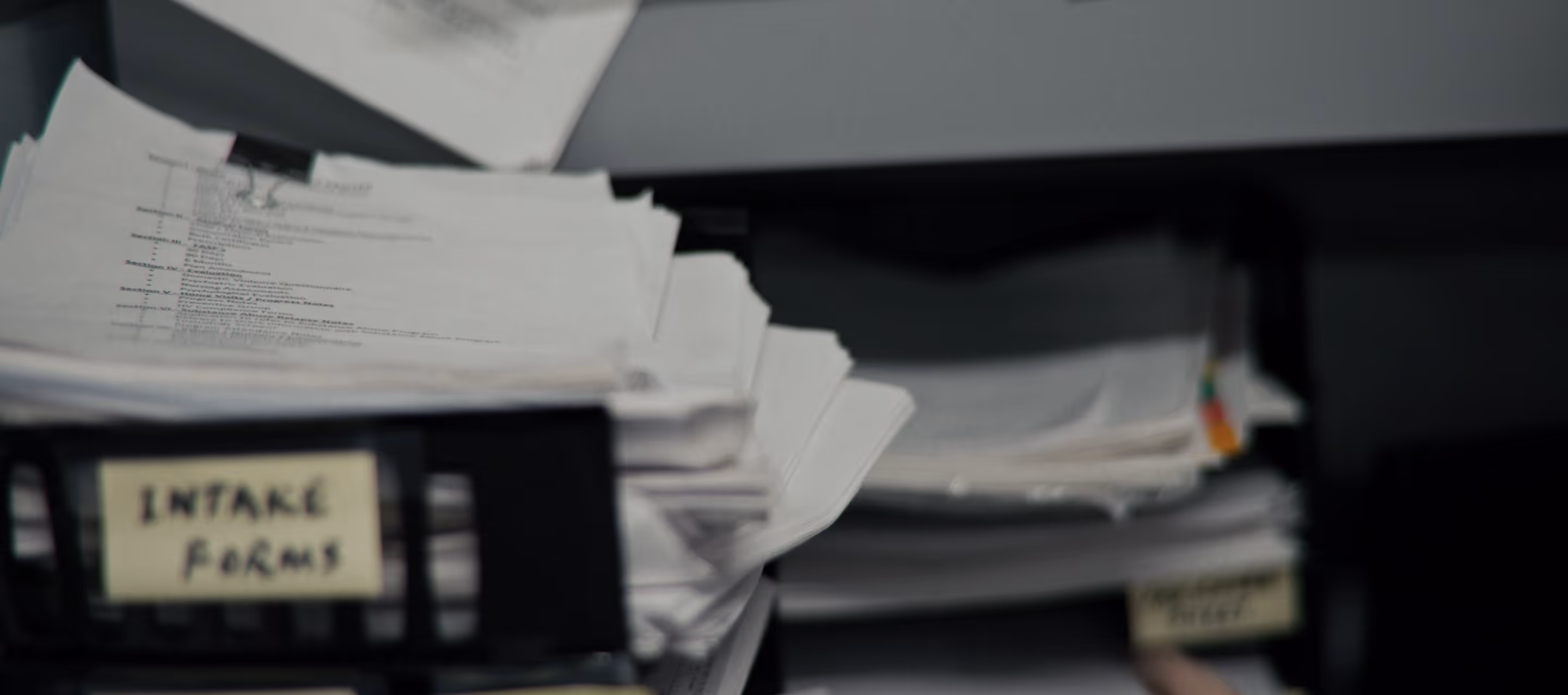 Stacks of paper documents organized in trays with labels, one labeled 'INTAKE FORMS'.