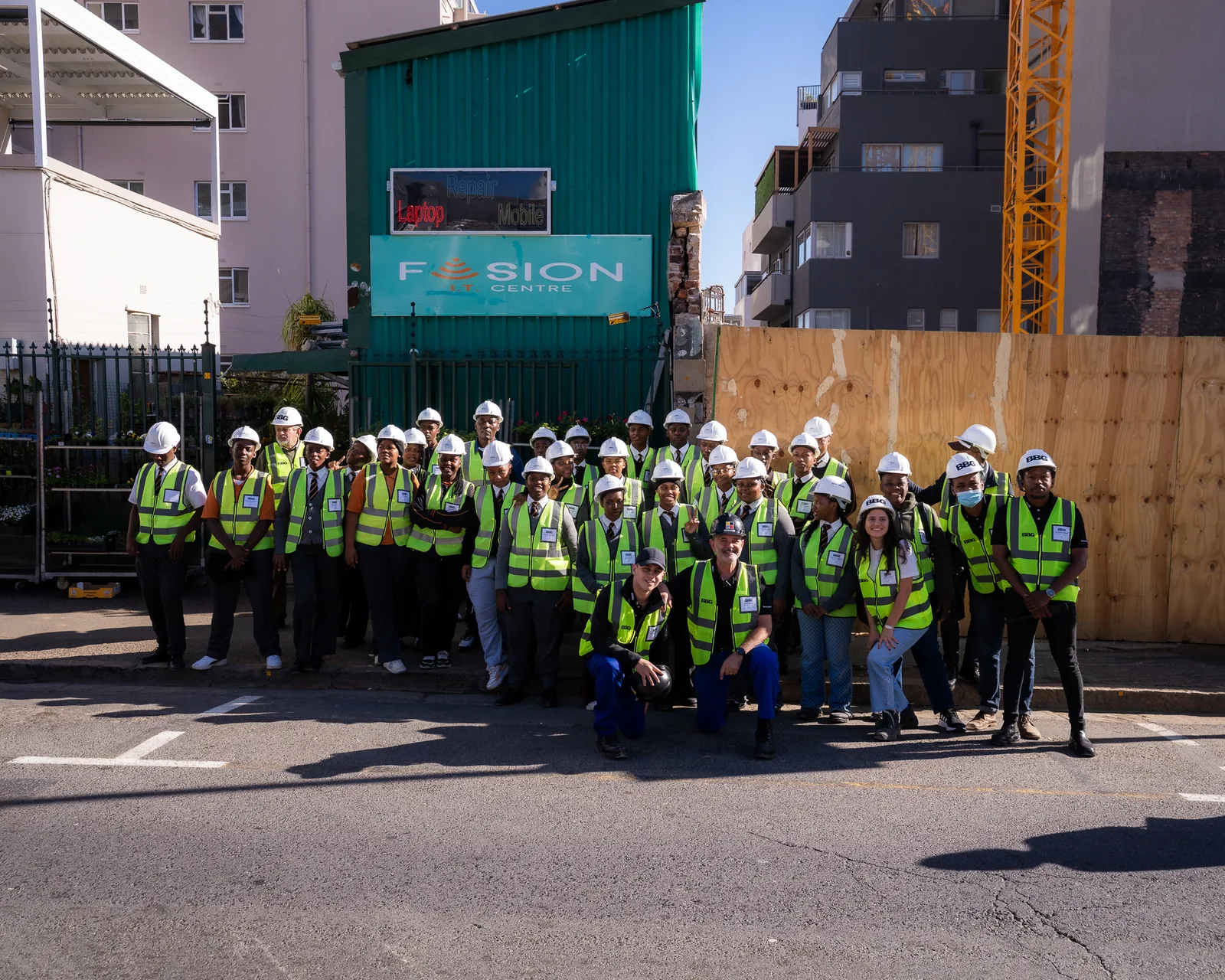 A group of Hands On learners and Berman Brothers Group staff in hard hats and high-visibility vests outside a Cape Town construction site