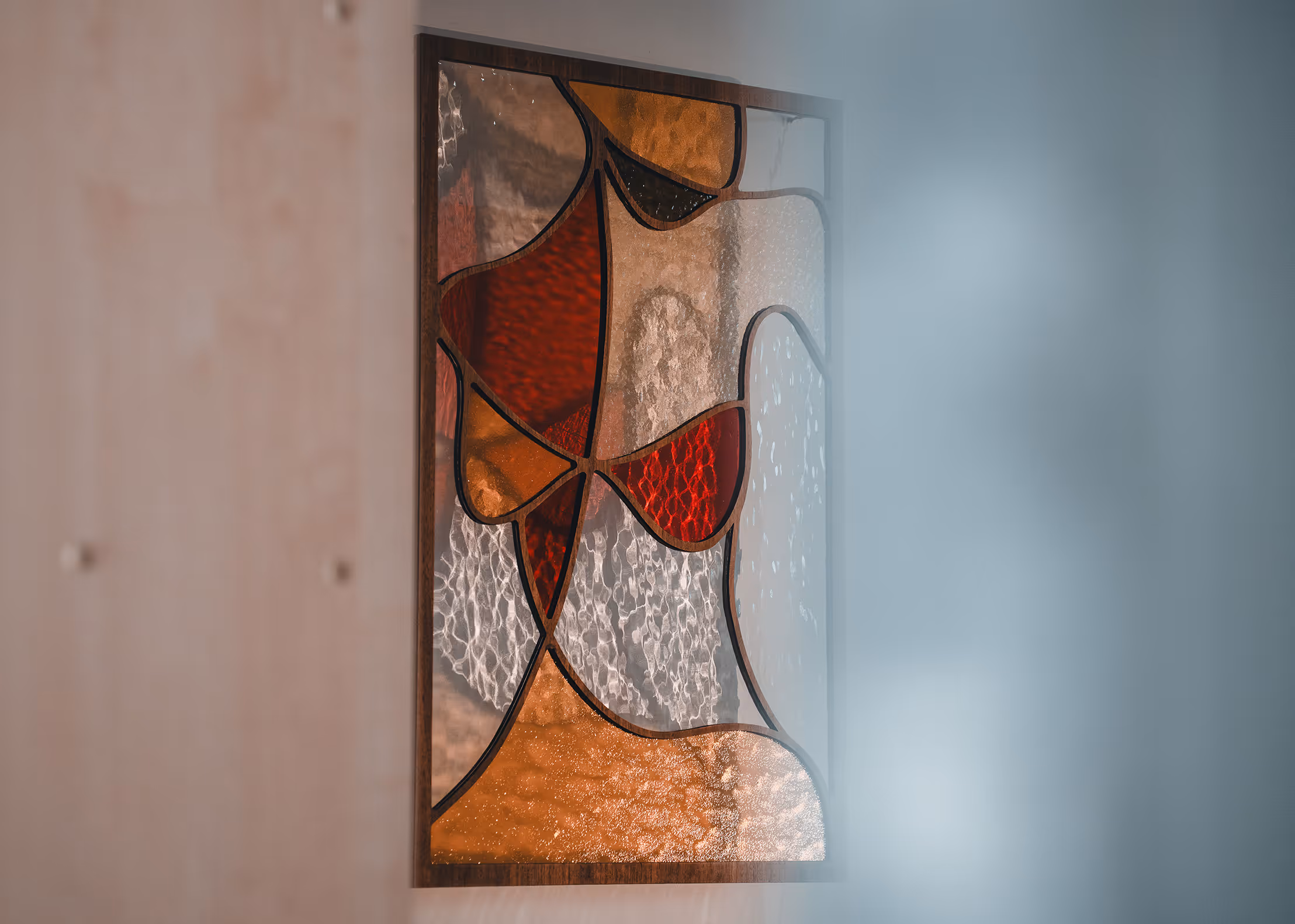Abstract stained glass artwork with red, amber, and textured clear glass pieces in a wooden frame.