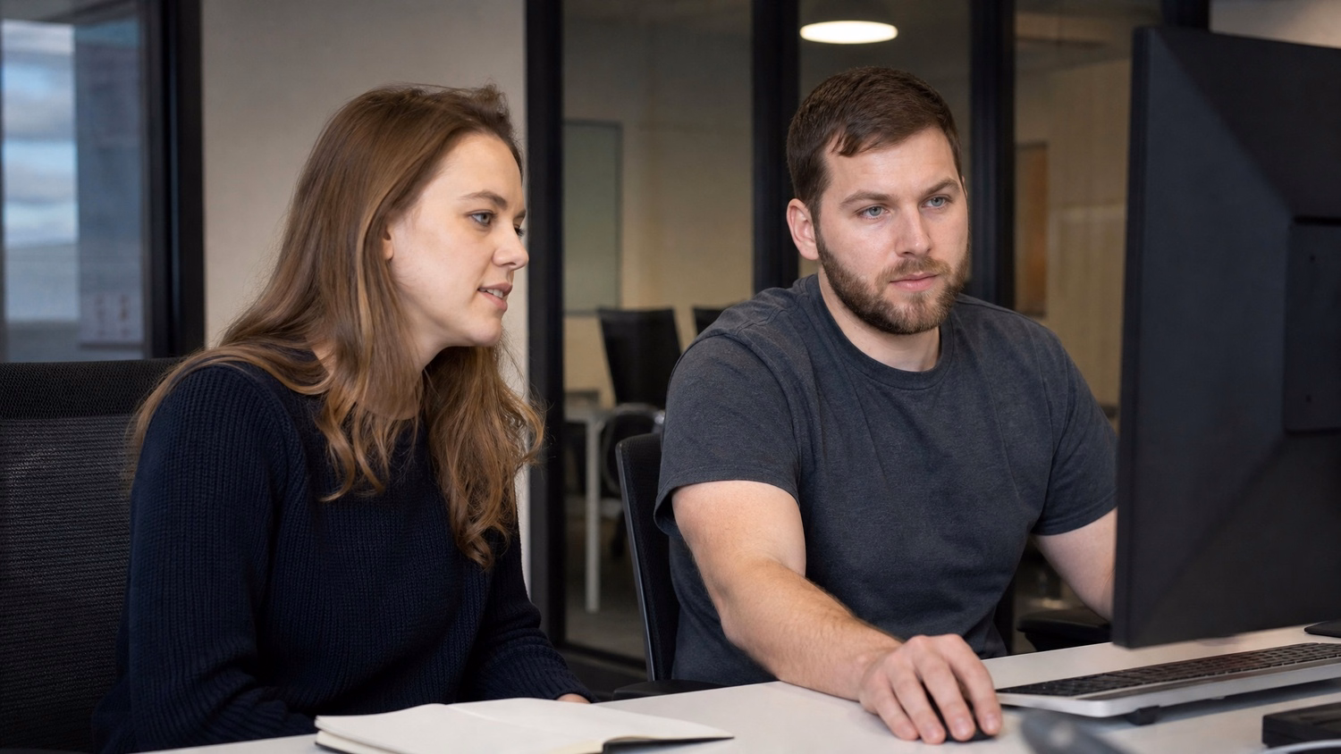 SIDE-BY-SIDE PAIR An IT professional two people seated side by side reviewin