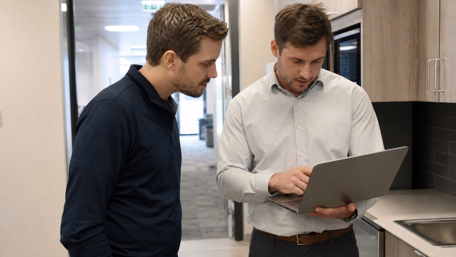 INFORMAL HUDDLE An IT professional two people standing and talking near a ki