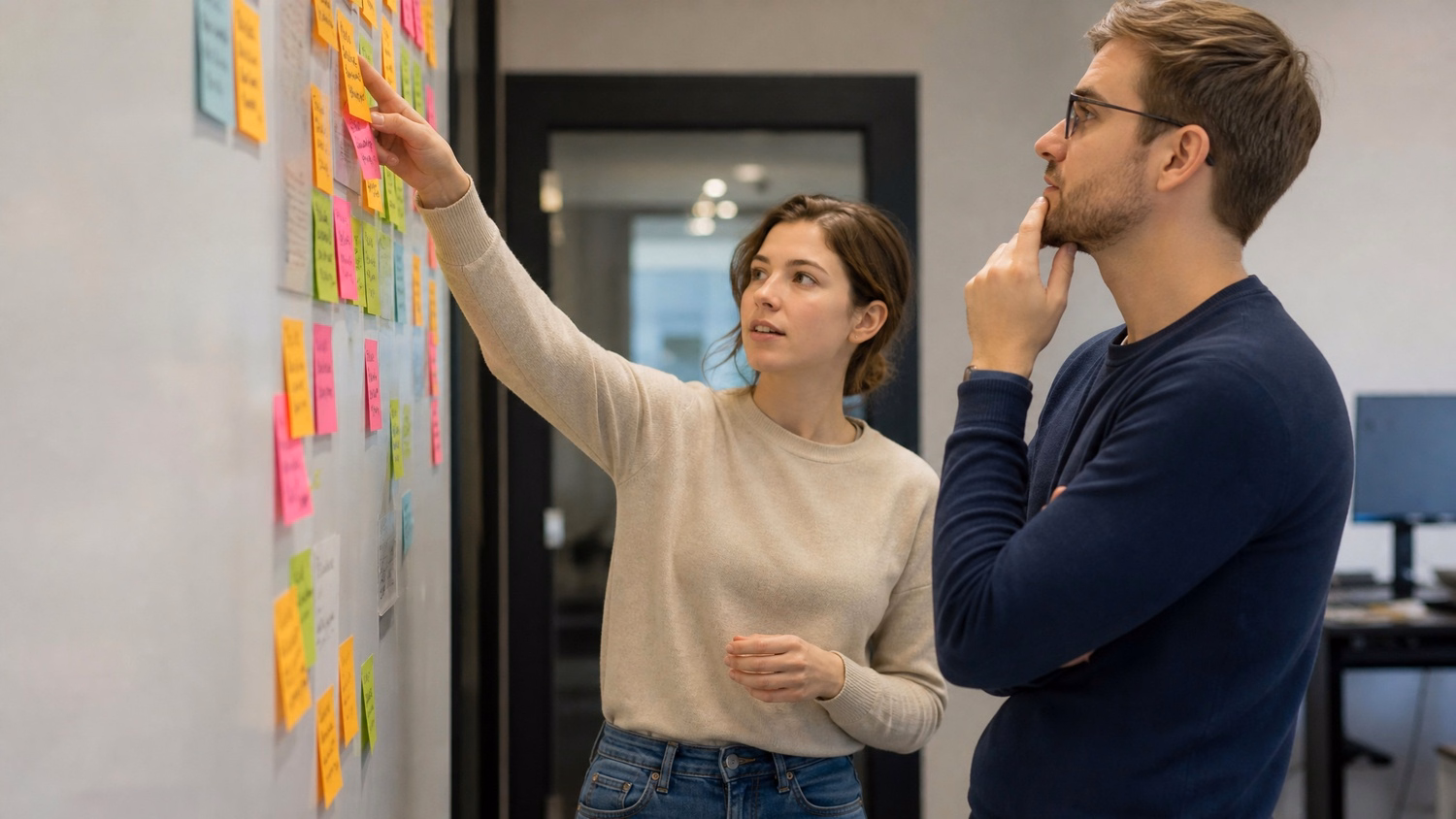 STICKY NOTE WALL An IT professional two people standing at a wall covered wi