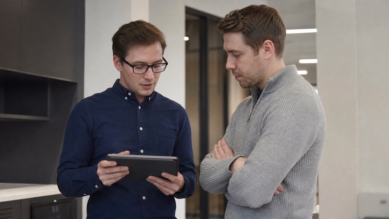 INFORMAL HUDDLE An IT professional two people standing and talking near a ki