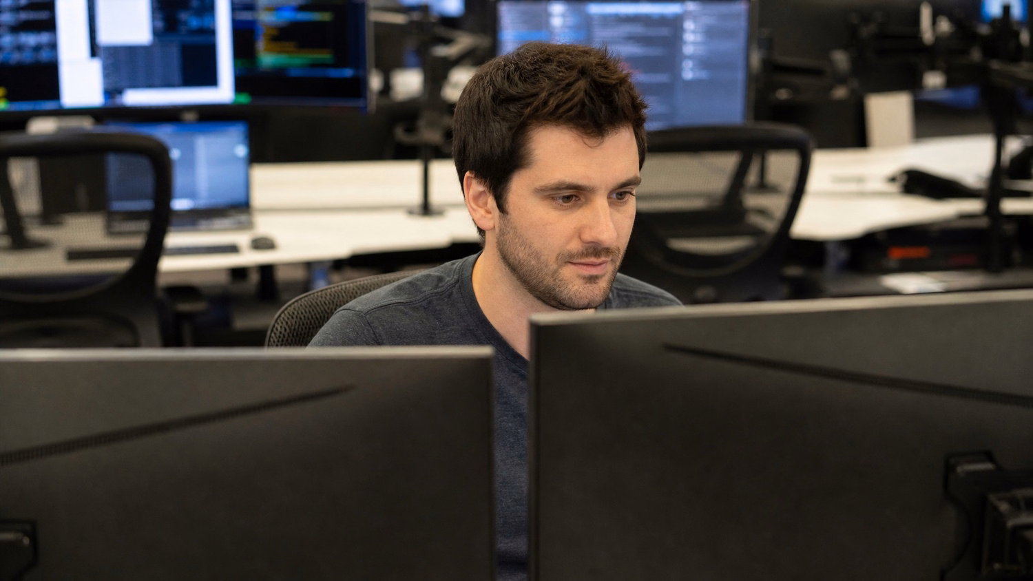 Man reviewing code on dual monitors at desk 55 chars