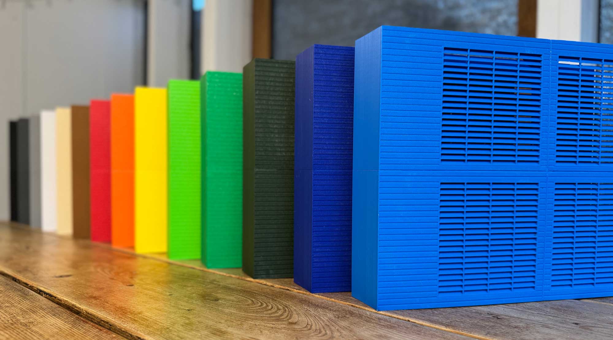 A range of Trimley fan convectors displaying a gradient of colors from black, gray, white, brown, red, orange, yellow, two shades of green, two shades of blue.