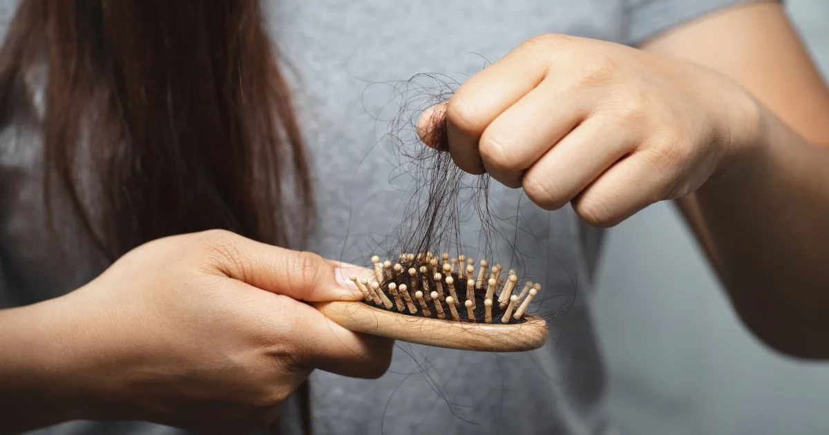 Woman looking at a hairbrush with significant hair shedding