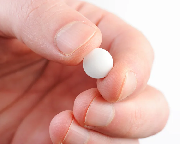 White Wegovy pill held between fingers showing size of oral semaglutide tablet