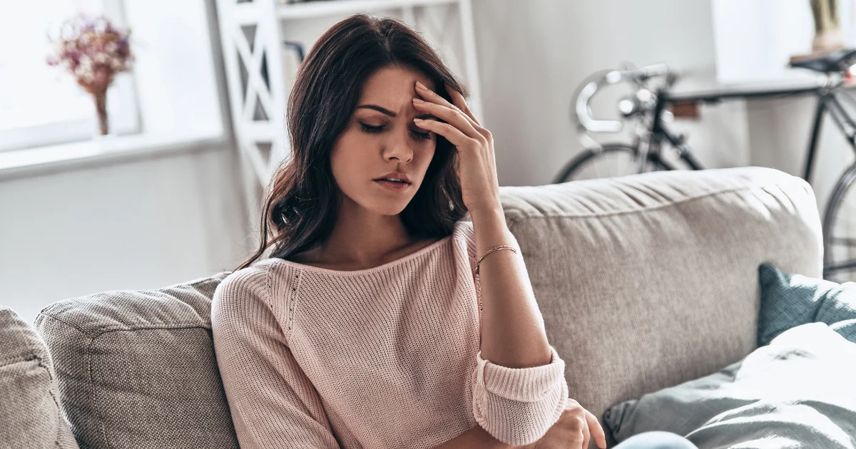 Woman experiencing severe headache and nausea at home, common symptoms requiring emergency medical attention