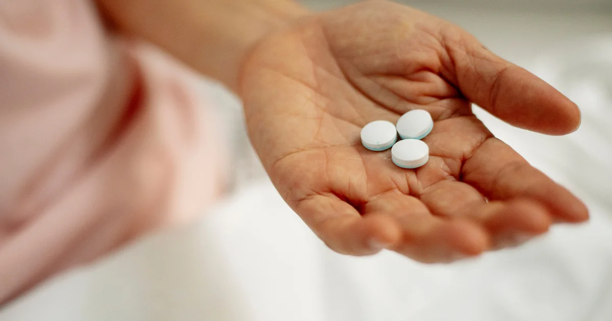 women holding out a handful of weight loss pills
