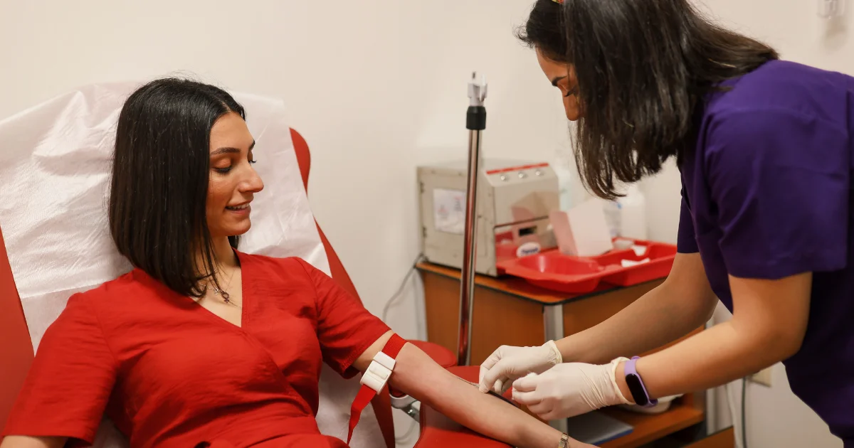 Smiling patient having a venous blood sample taken by a clinician in a clinic setting