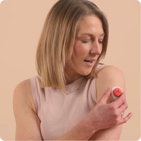 Woman holding a small round device against her upper arm, appearing to prepare for or complete a blood sample collection.