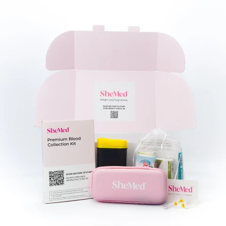 SheMed Premium Blood Collection Kit including a pink carrying case, collection container, and medical supplies inside an open pink box.