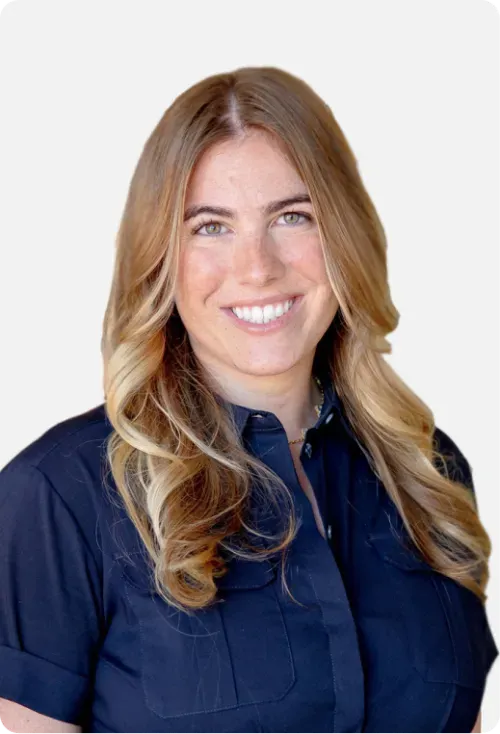 Smiling woman with long blonde hair wearing a dark blue button-up shirt against a plain white background.