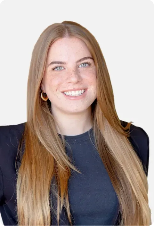 Smiling woman with long straight blonde hair wearing a black blazer and gold hoop earrings against a white background.