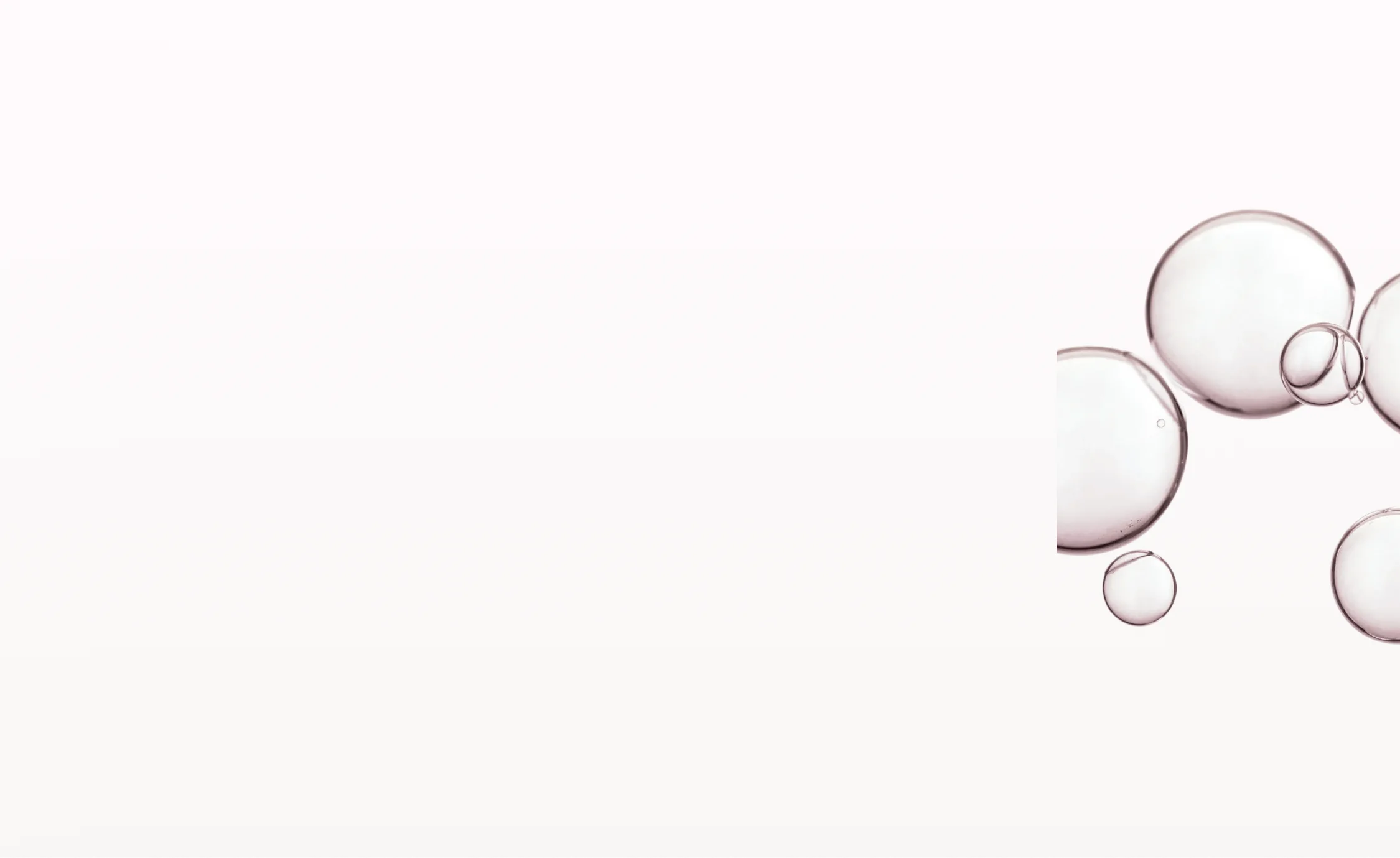 Transparent soap bubbles of various sizes floating on a white background clustered to the right.