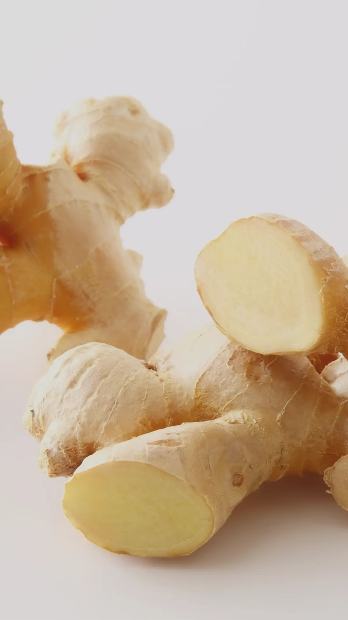 Fresh ginger root with one piece cut open showing the light-yellow interior.
