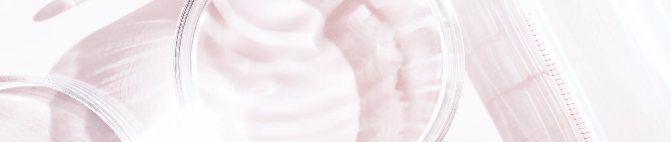 Close-up of transparent laboratory glassware with light reflections on a beige background.