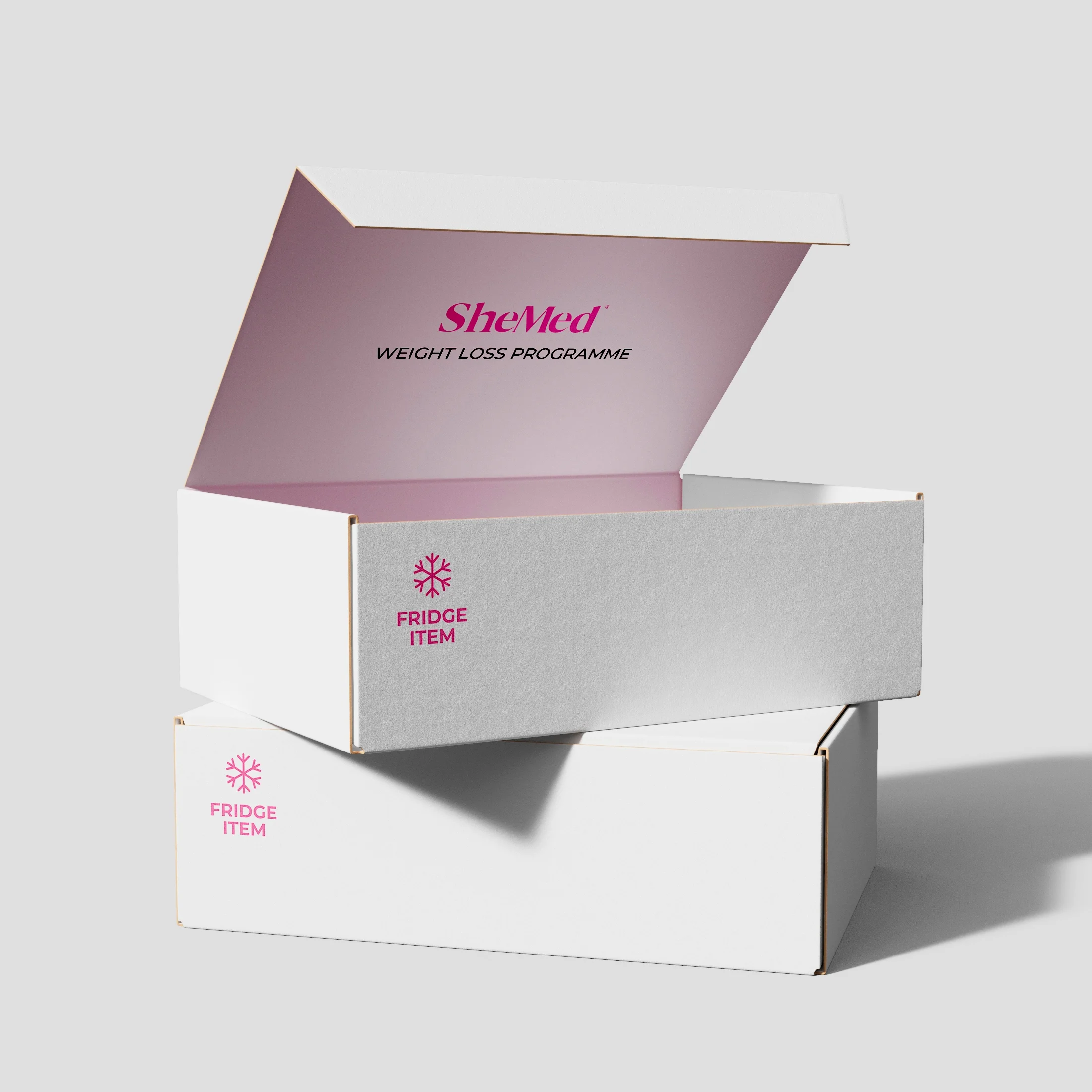 White cardboard boxes stacked, with the top box open showing pink interior and text 'SheMed Weight Loss Programme' and 'Fridge Item' label on both boxes.