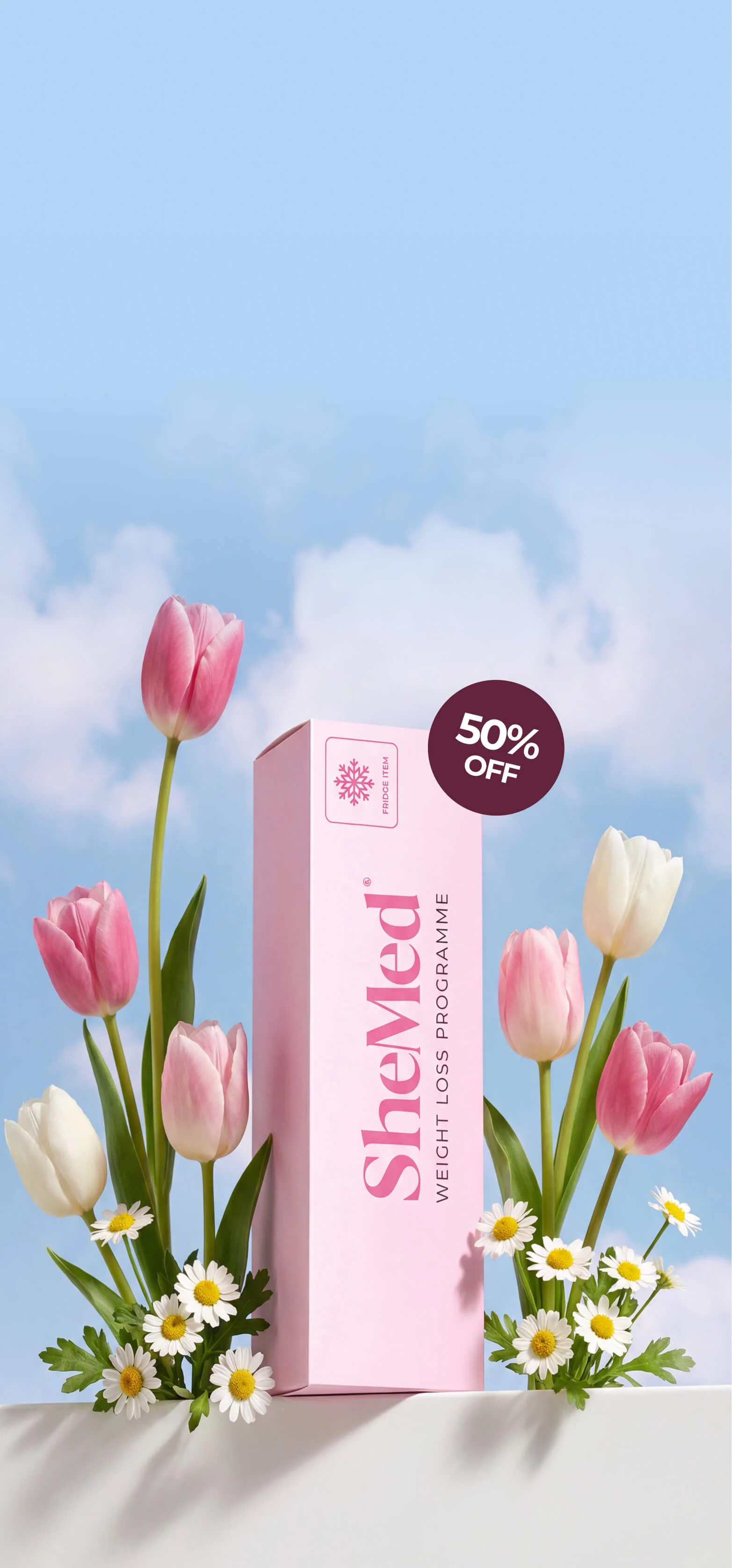 Pink SheMed weight loss programme box surrounded by pink and white tulips and daisies with a 50% off label, against a blue sky with clouds.