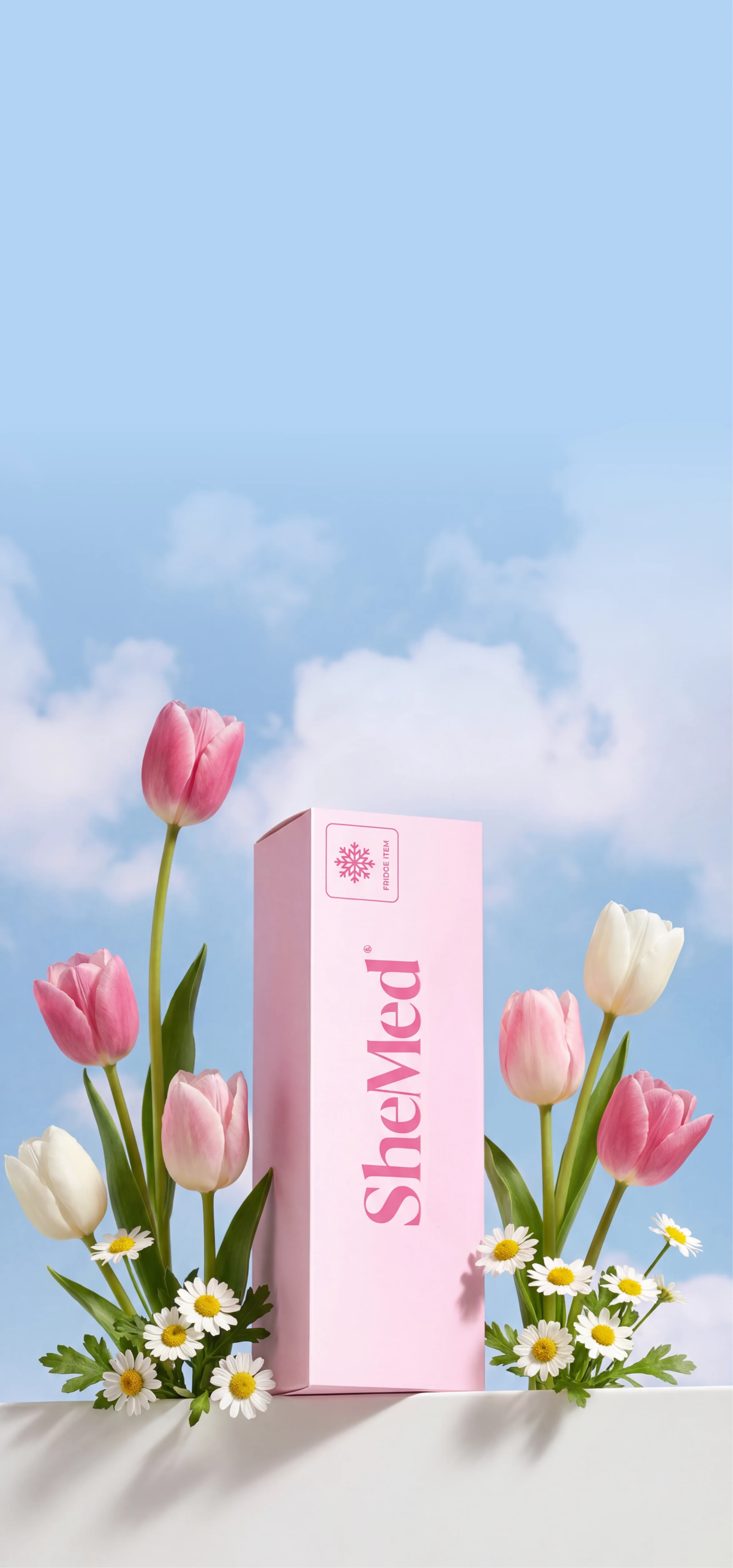 Pink SheMed product box surrounded by pink and white tulips and white daisies against a blue sky with clouds.