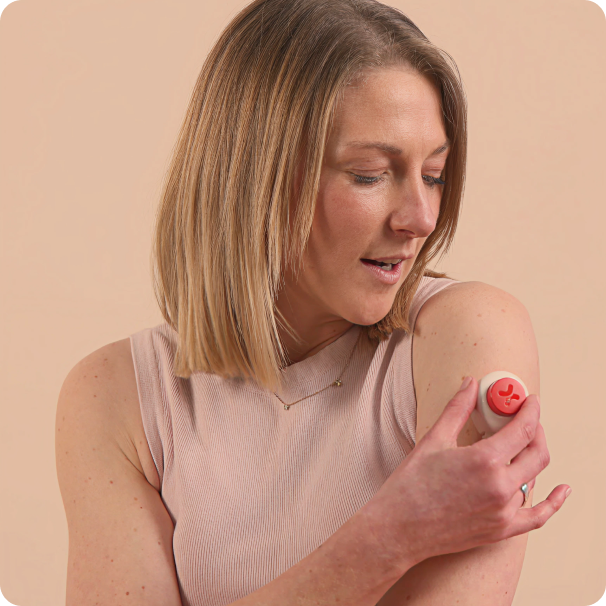 A woman using a SheMed at-home needle-free blood collection device on her upper arm, part of the free health screening included in the SheMed oral weight loss programme for UK women.