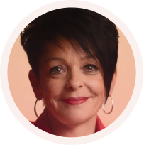 Portrait of a smiling woman with short dark hair and hoop earrings on a peach background.