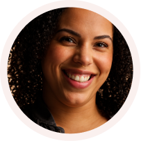 Smiling woman with curly hair against a dark background in a circular frame.