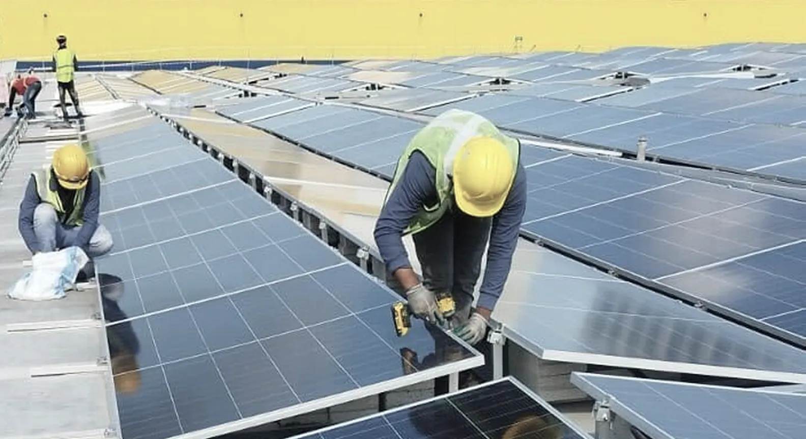 Workers installing solar panels on a rooftop under a clear sky.