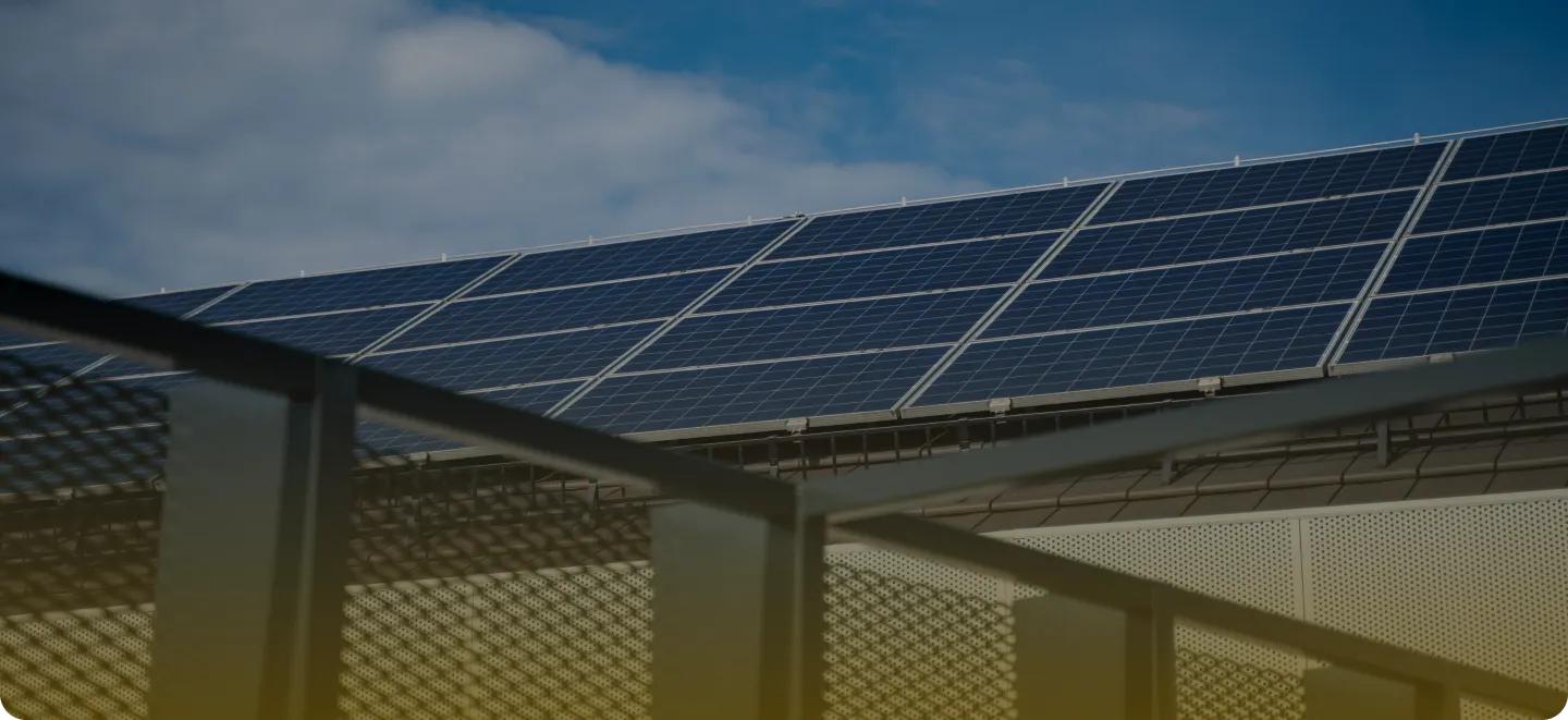 Close-up of solar panels installed on a rooftop under a cloudy sky.