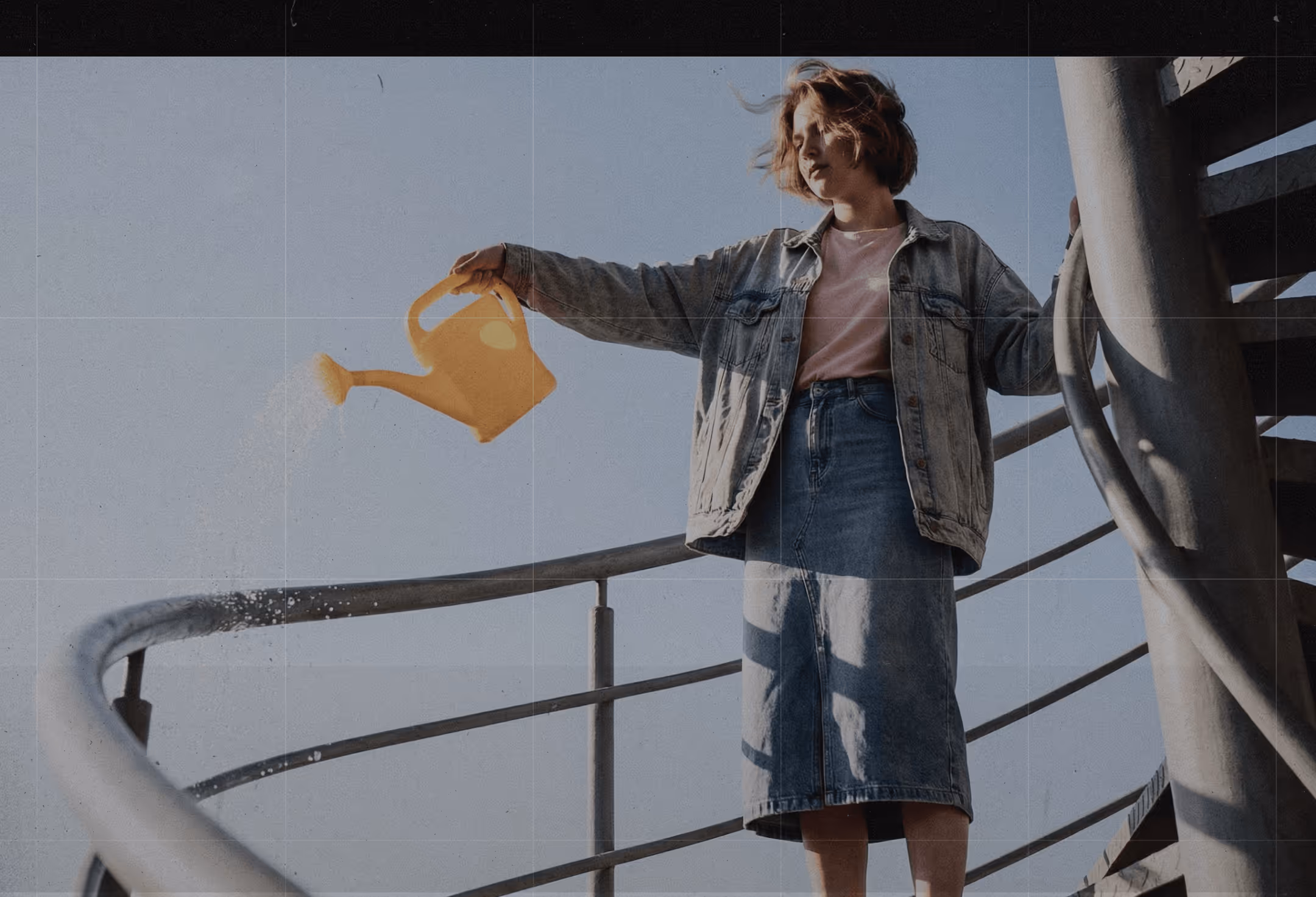 Person in denim jacket and skirt watering plants with a yellow watering can on a spiral staircase.