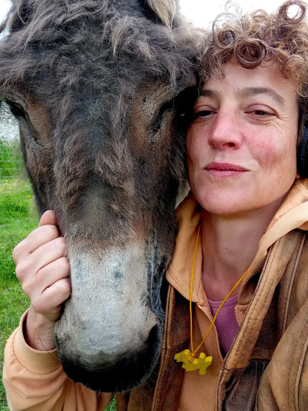 Solène qui sourit aux côté d'un âne gris