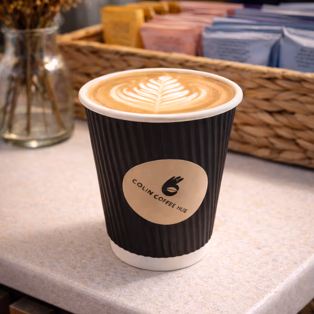 Latte in a Colin Coffee Hub takeaway cup with latte art on the cafe counter.