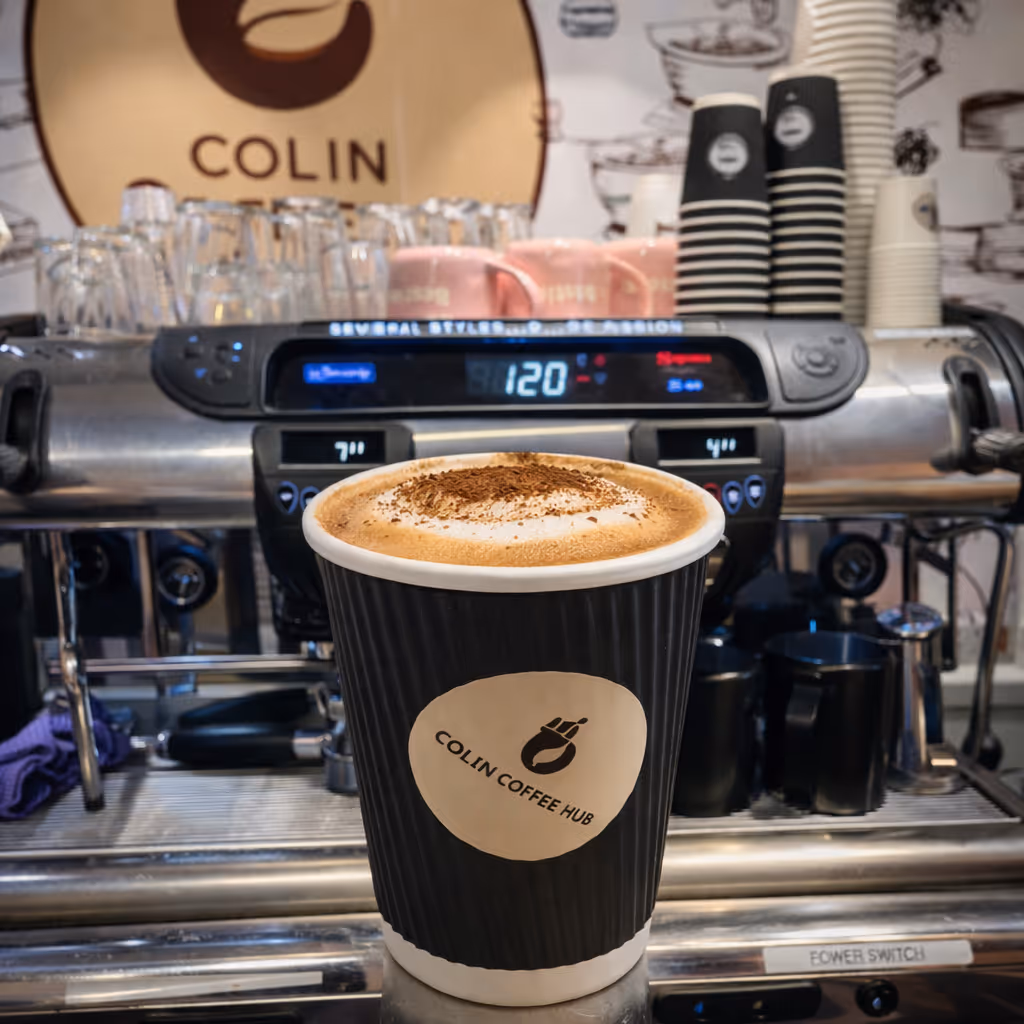 Cappuccino in a Colin Coffee Hub takeaway cup in front of the espresso machine.