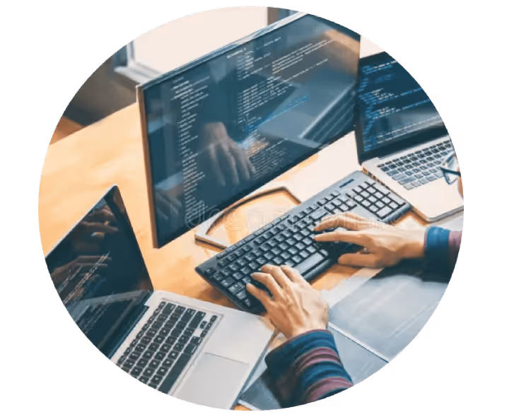 Person typing on keyboard with multiple computer screens displaying code on a wooden desk.
