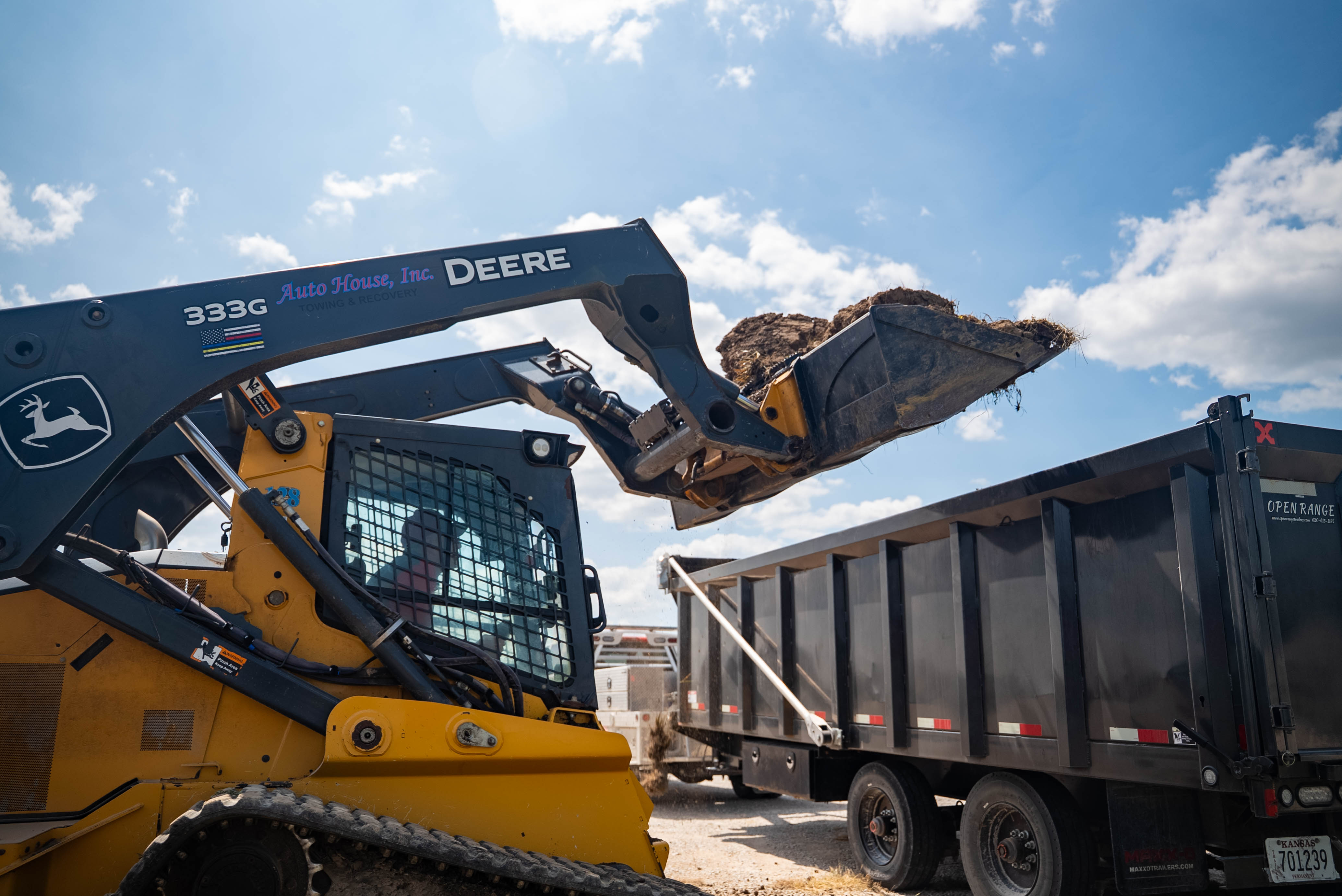 Auto House skid steer loading contaminated soil into a dump trailer