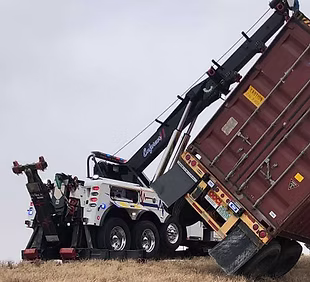 Auto House rotator recovering a tipped shipping container off an embankment