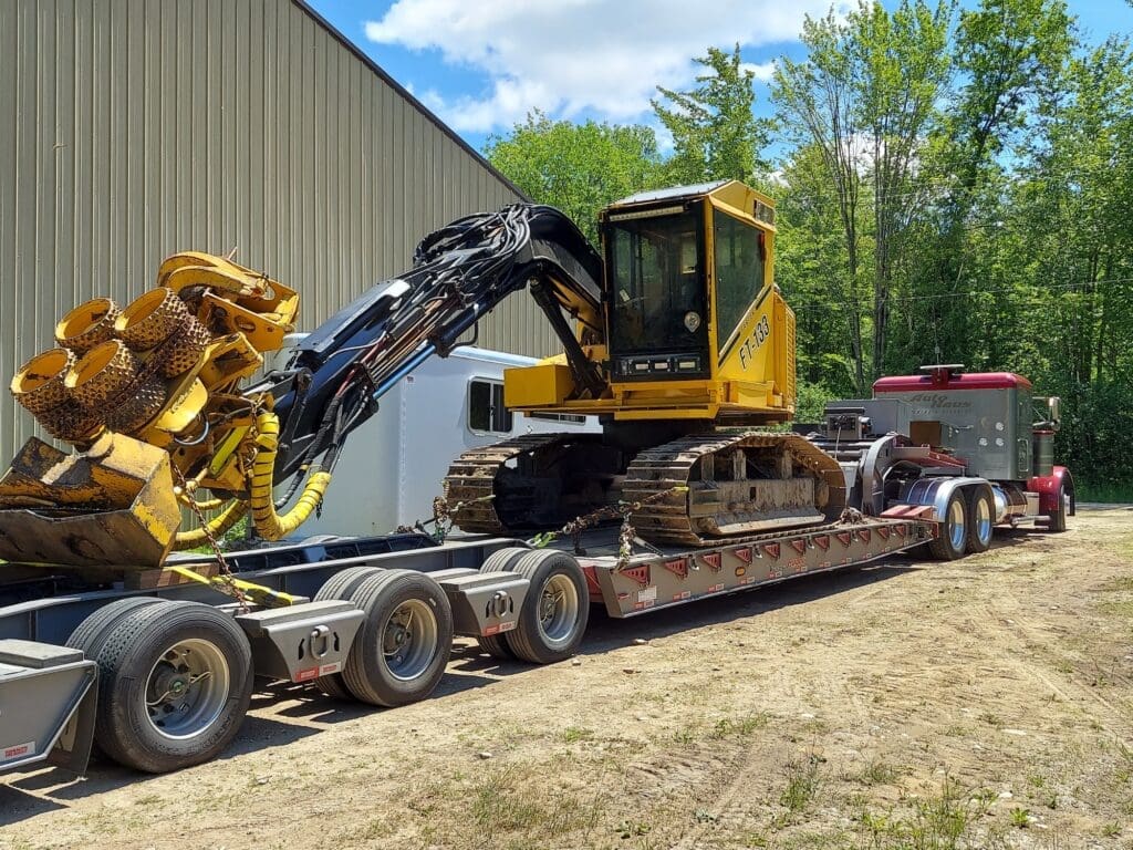 Auto House lowboy hauling a yellow forestry machine
