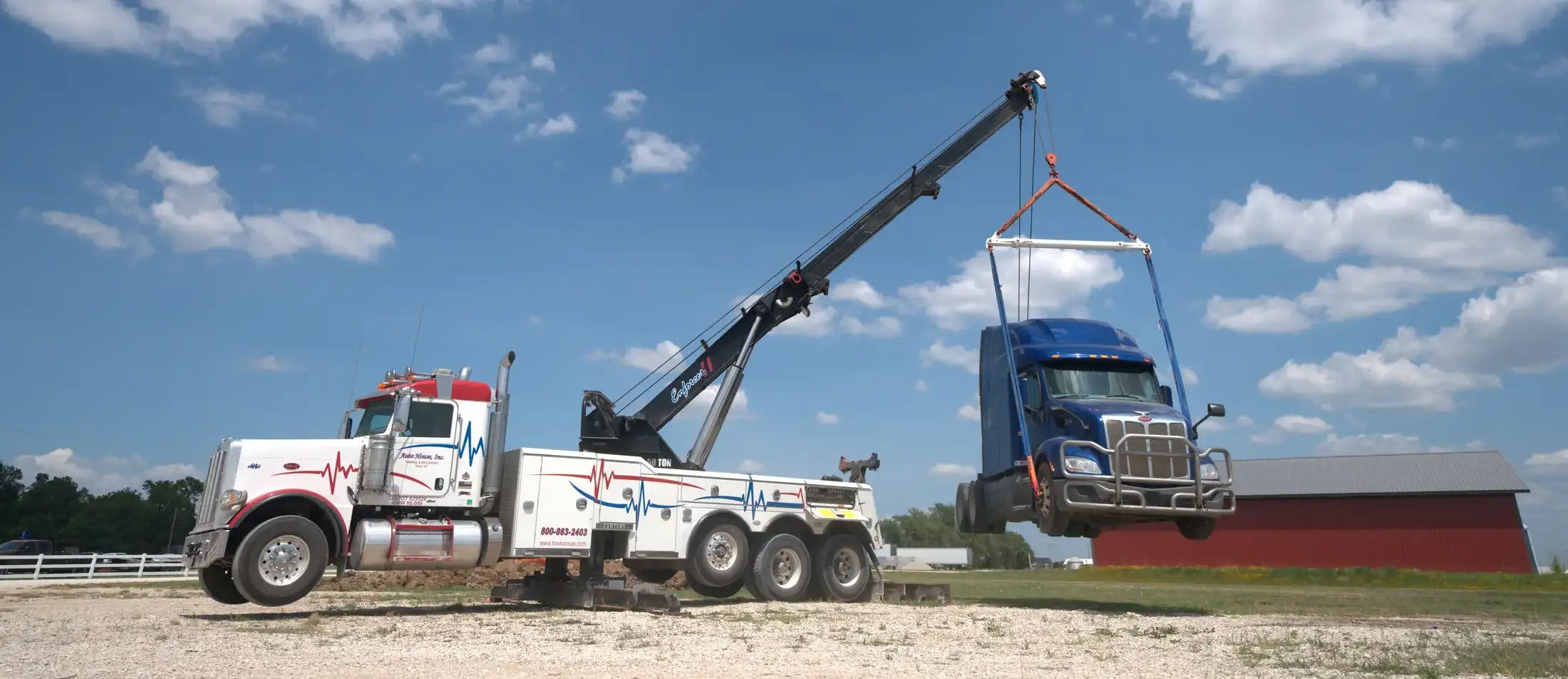 Auto House rotator wrecker lifting a blue Peterbilt semi tractor