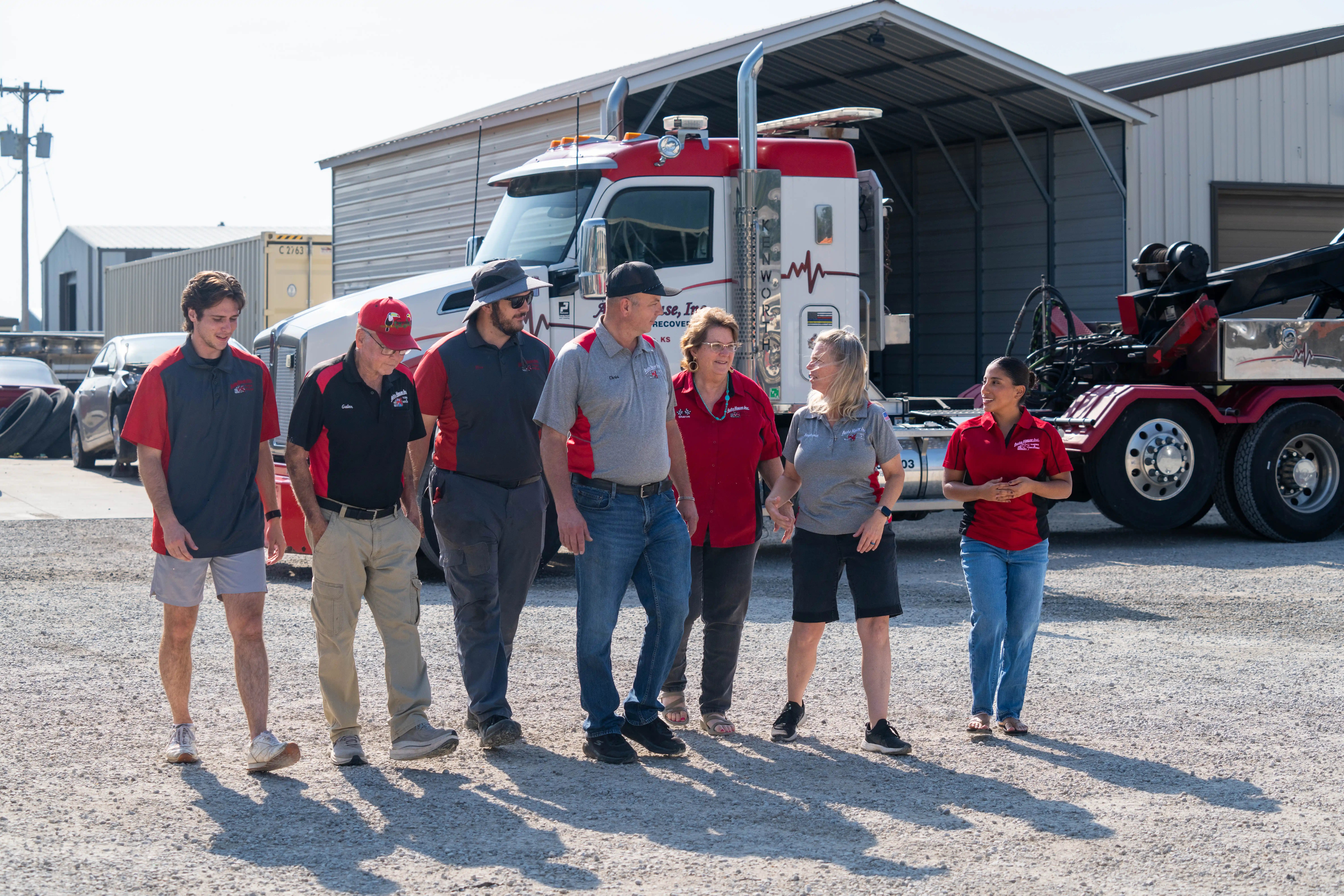 The Auto House team walking across the yard past a heavy wrecker